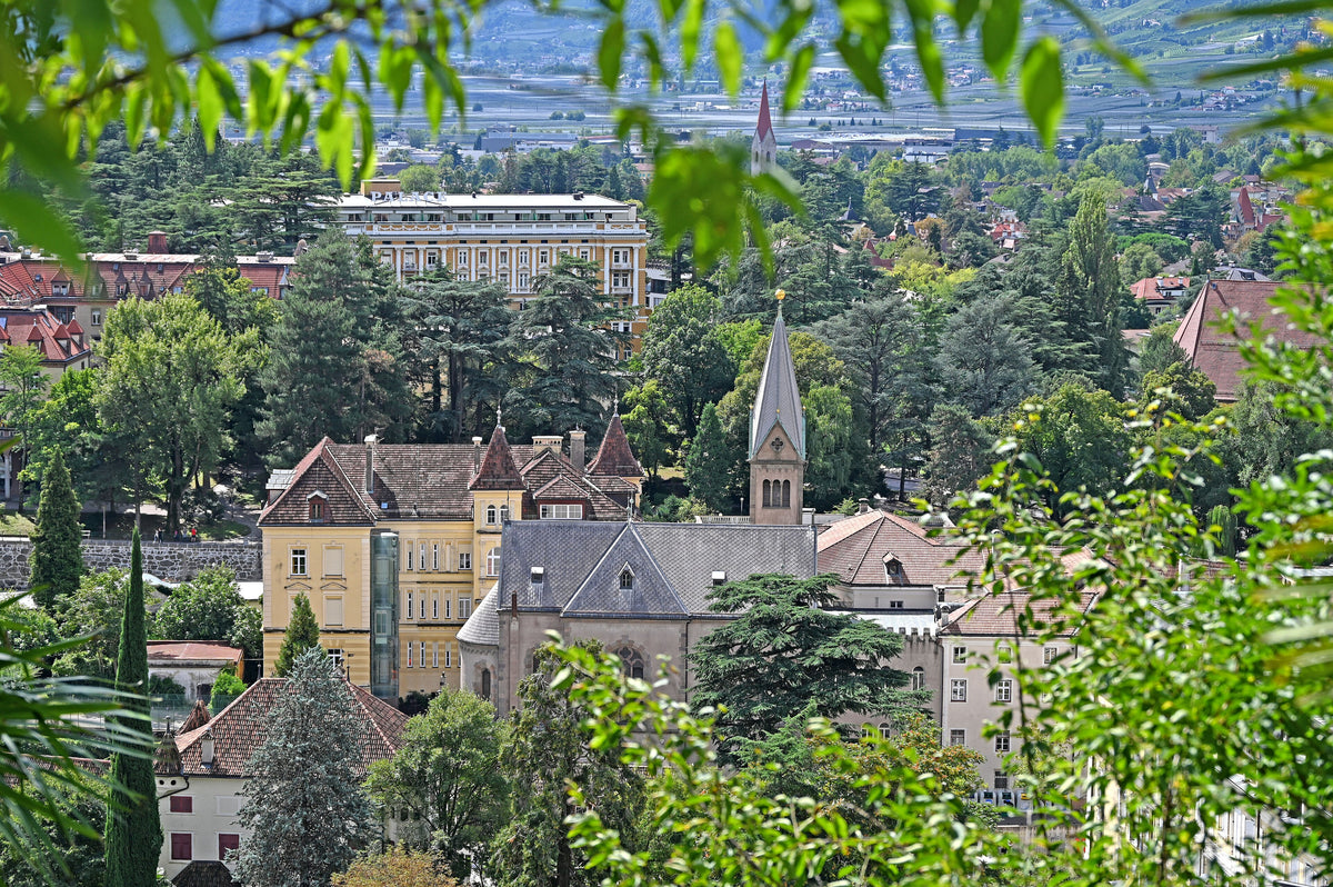 Merano's old town and the Herz Jesu church seen from the hillside, with Palace Merano visible beyond the rooftops