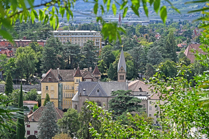 Merano's old town and the Herz Jesu church seen from the hillside, with Palace Merano visible beyond the rooftops