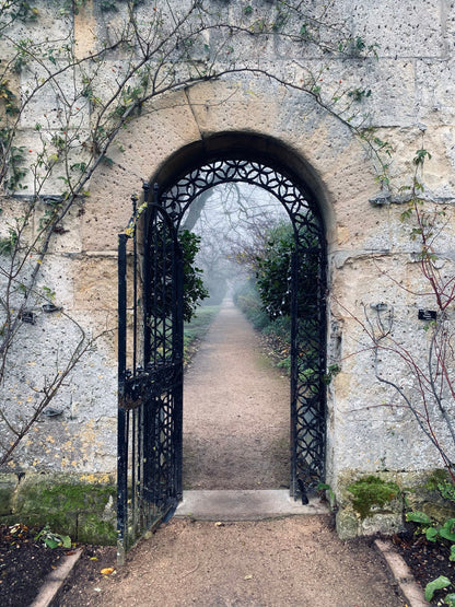 A stone archway leads into a misty walled garden.
