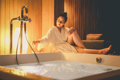 A woman resting in a warm bath in low golden light, Aquarias Spa at Whatley Manor