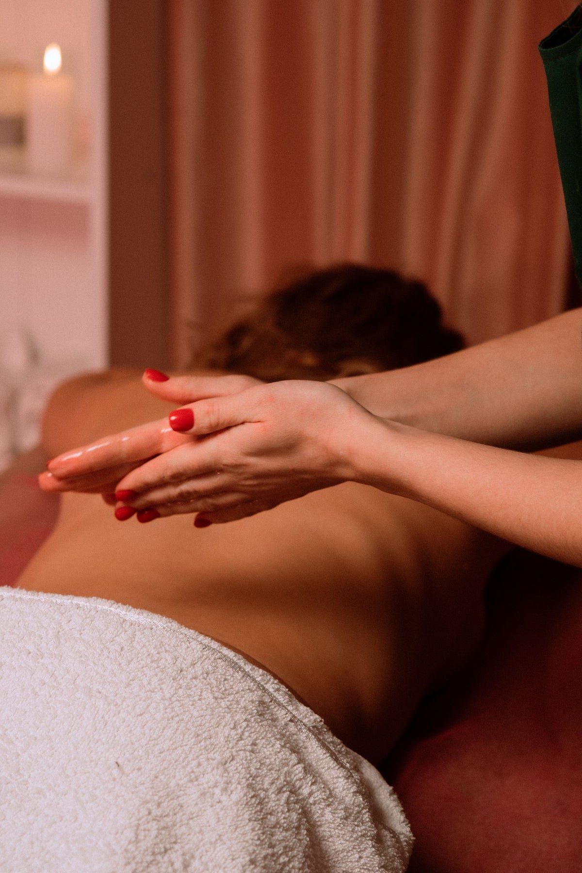 Hands mid massage on a guest's back by warm candlelight