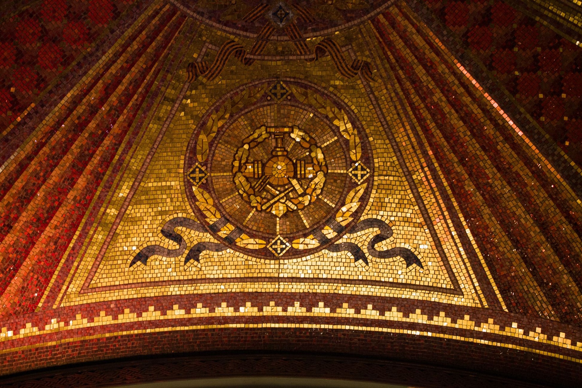 Gold mosaic tesserae catching low light, the gilded oval reception that opens the spa