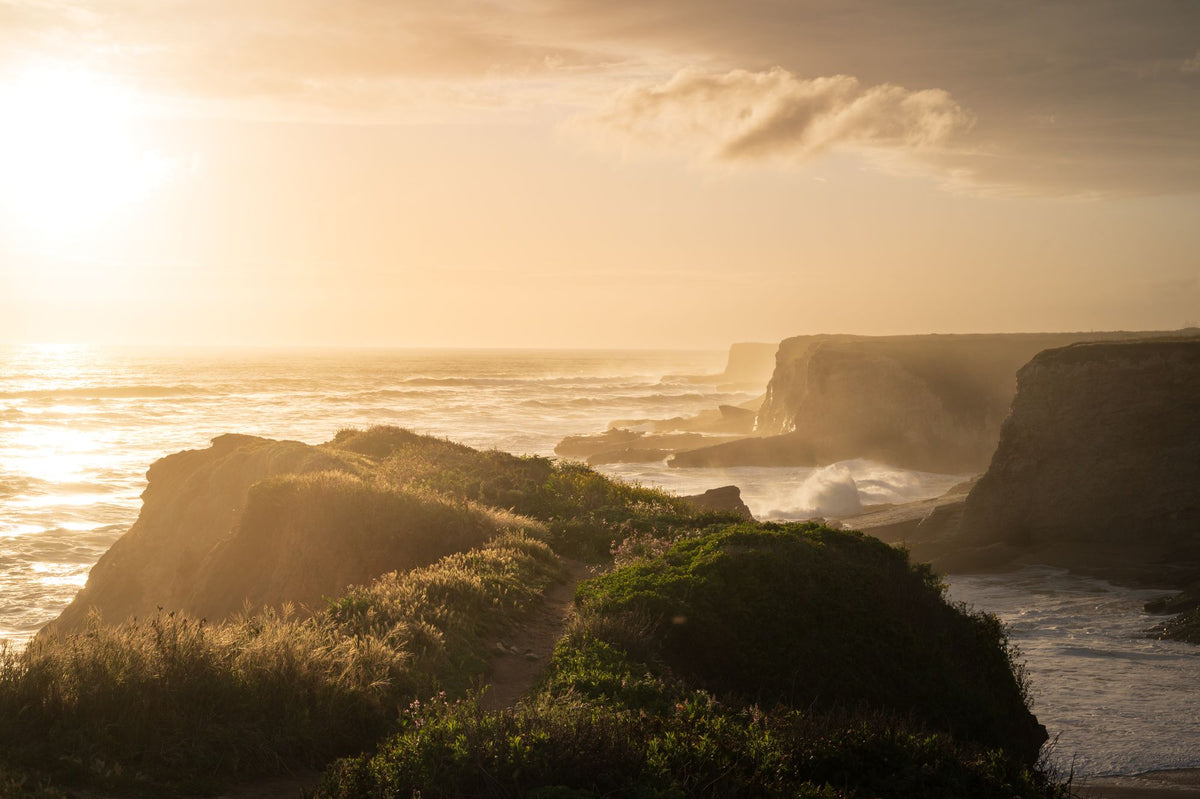 Golden hour light over the coast path and cliffs near Carne Bay Spa at The Nare