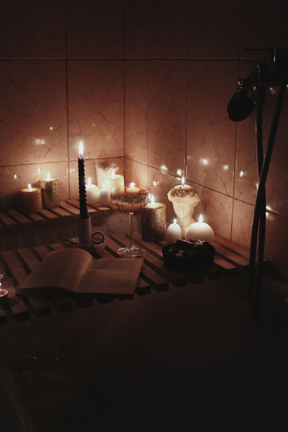 Candles burning beside a deep bath, the warm low light of an evening soak.