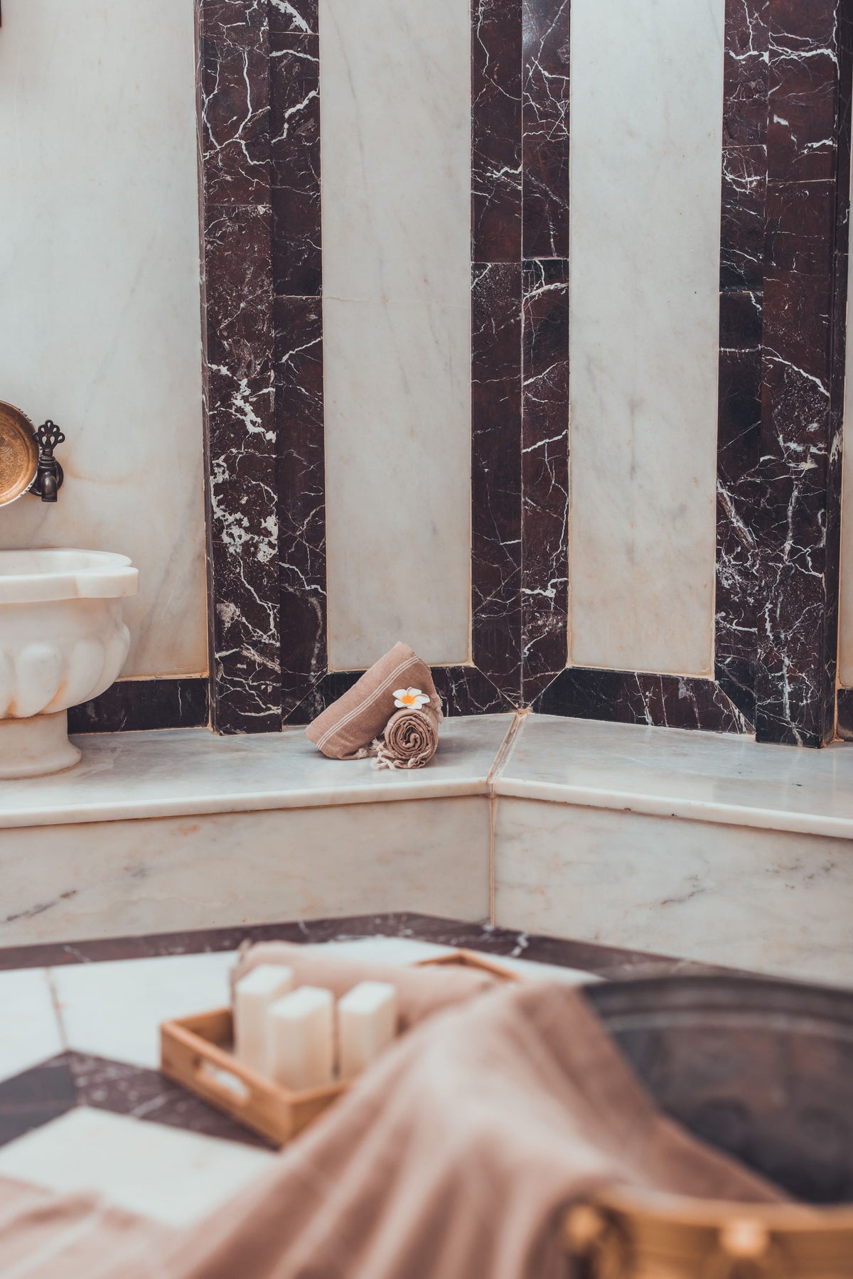 A marble steam room interior with a folded towel and candle, Ritz Paris Club & Spa.