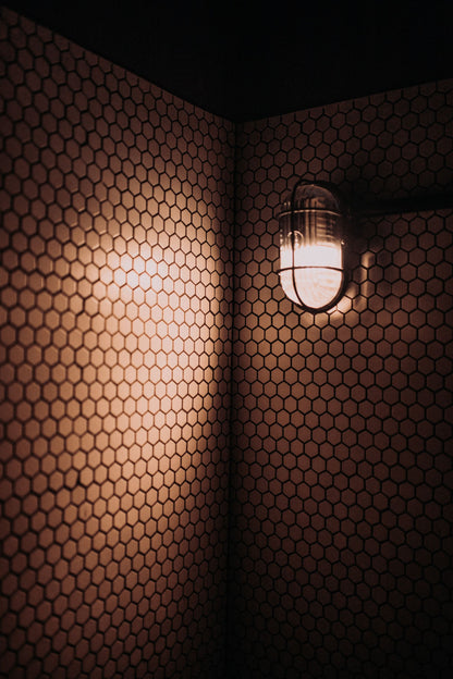 Warm lantern light on dark hexagonal tiles, evoking the Turkish suite at Arlington Baths Club