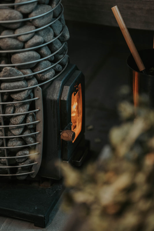 Firelight glowing inside a stone stacked sauna heater, The Cowshed Spa at Soho Farmhouse