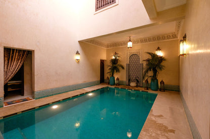 Indoor pool within a traditional riad, with arched stonework and warm light
