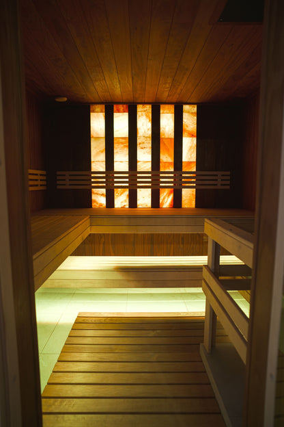 Warm lit wooden sauna interior with salt panel wall