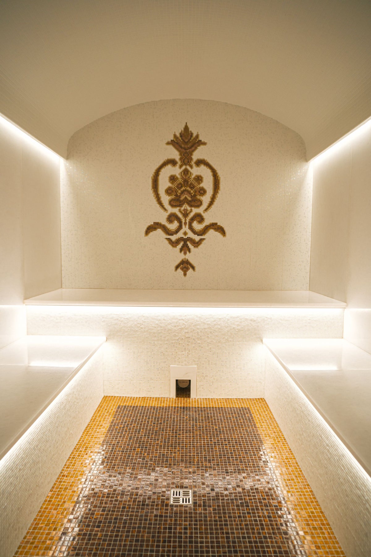 A mosaic lined steam room glowing gold, evocative of a citrine steam room