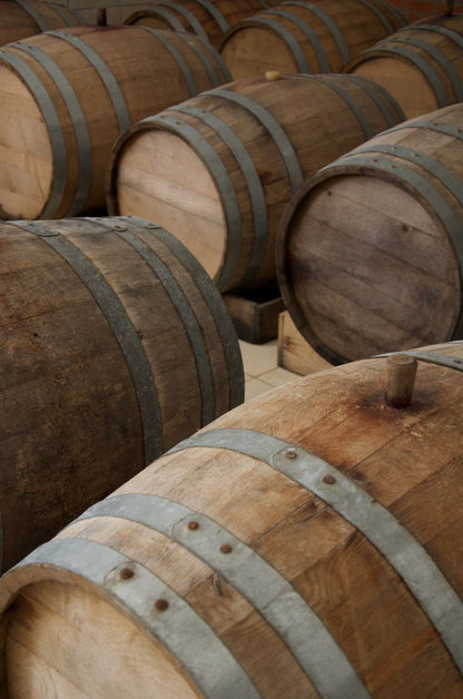 Stacked oak wine barrels with metal hoops, evoking the vinotherapy treatments at Hotel Marques de Riscal