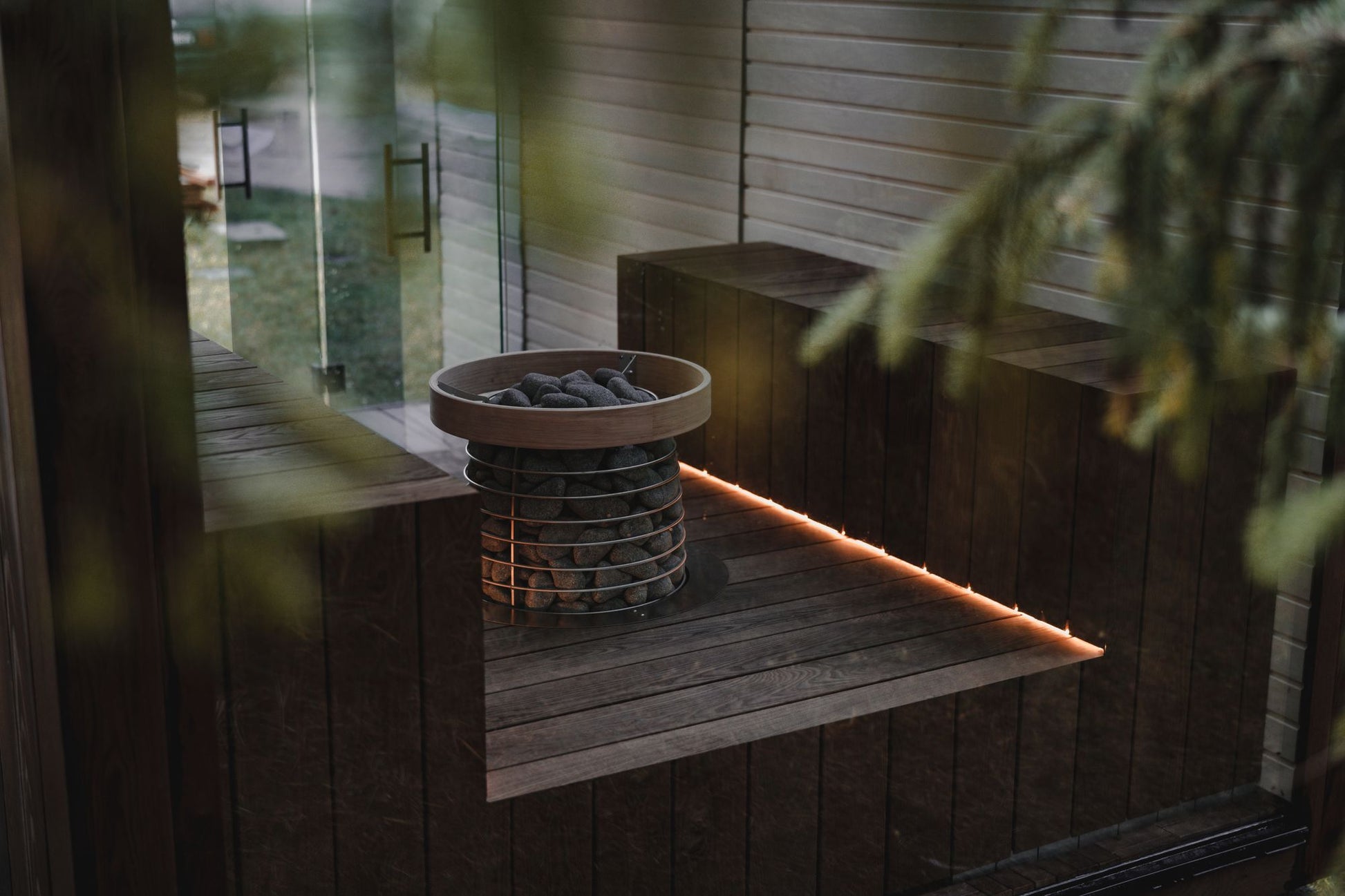 Sauna stones glowing in warm low light against dark wood, The Lanesborough Club & Spa