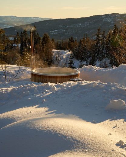 Steam rising from a wood fired hot tub on a snowy mountainside at sunset, evoking the heat and cold of an alpine spa in Courchevel