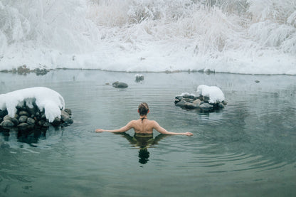 A bather resting in cold green water between snow covered rocks, The Cowshed Spa at Soho Farmhouse