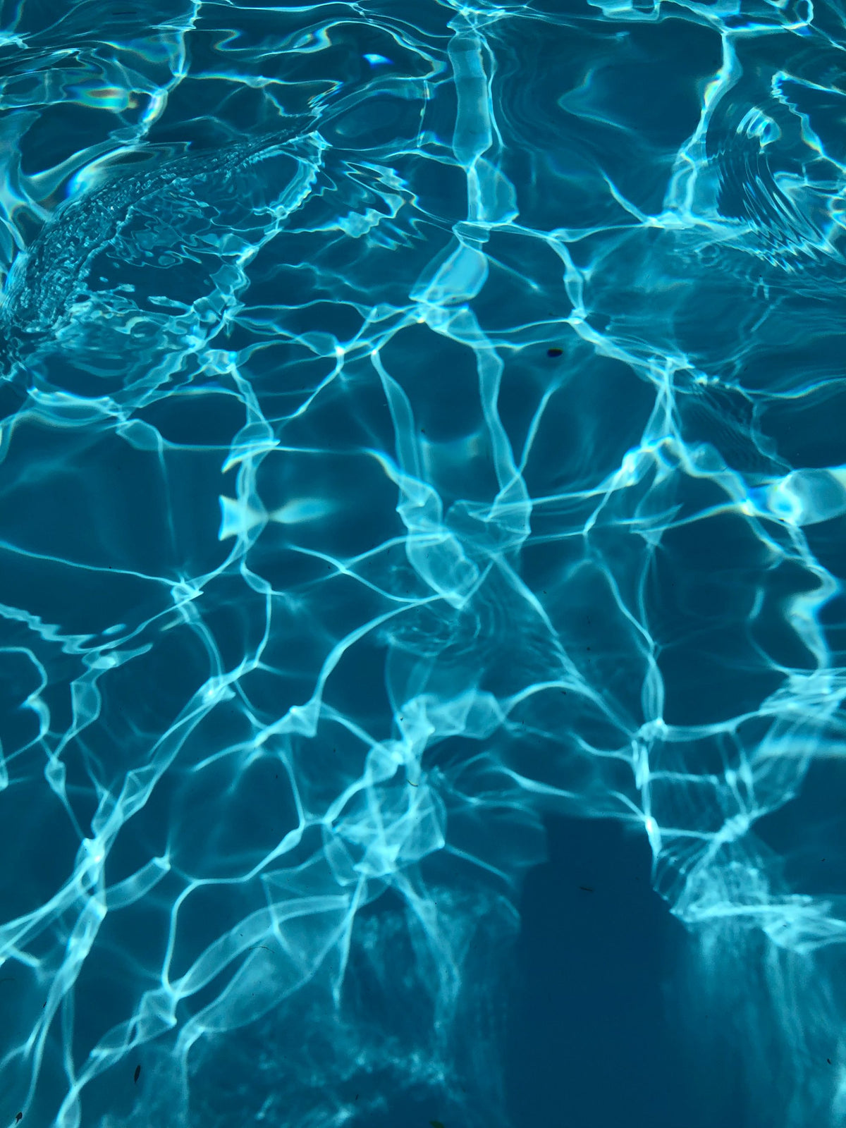 Crystalline light patterns rippling across pale blue pool water at a Paris Palace hotel spa