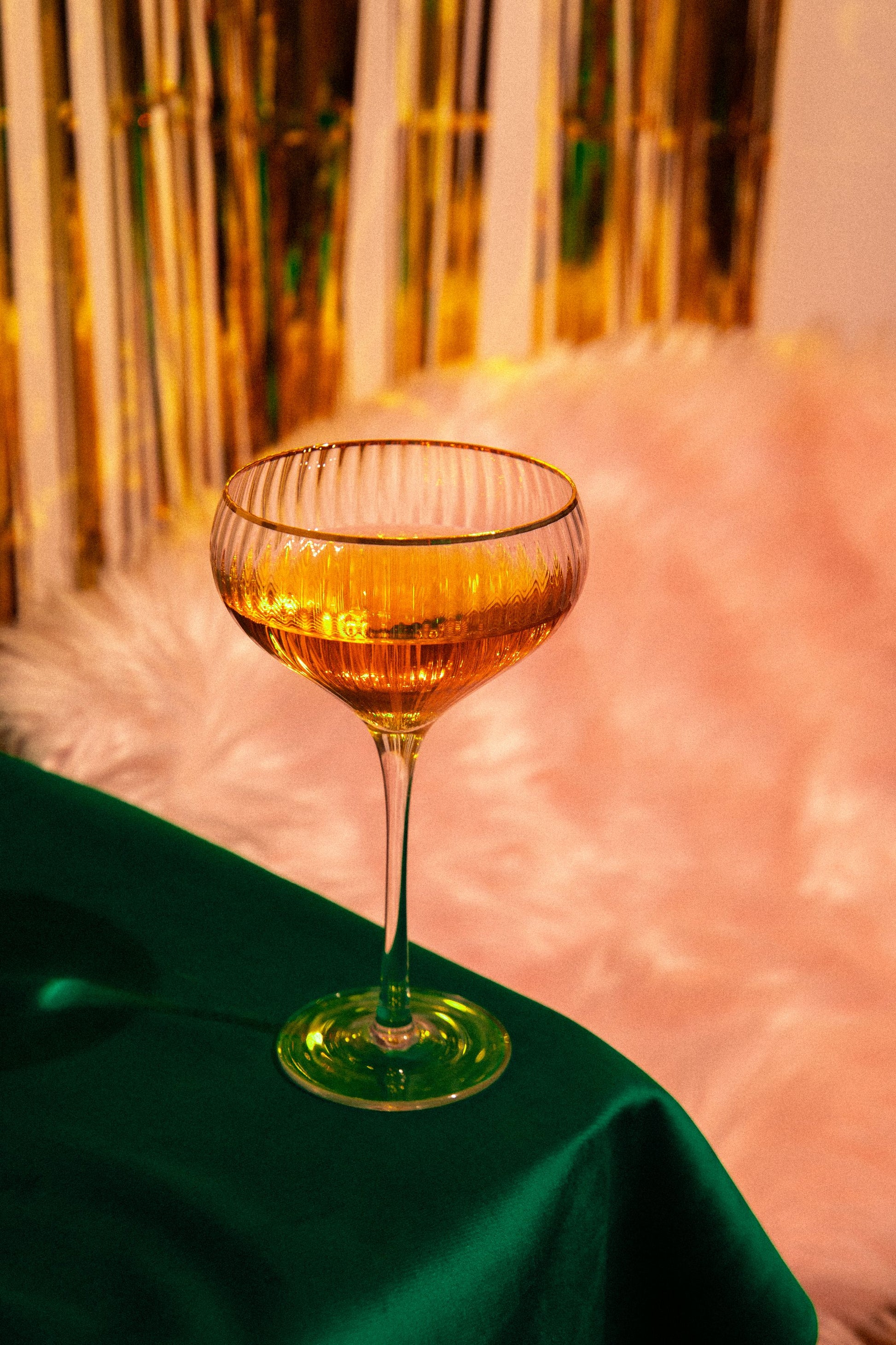 A gold cocktail glass on an emerald cloth in evening light