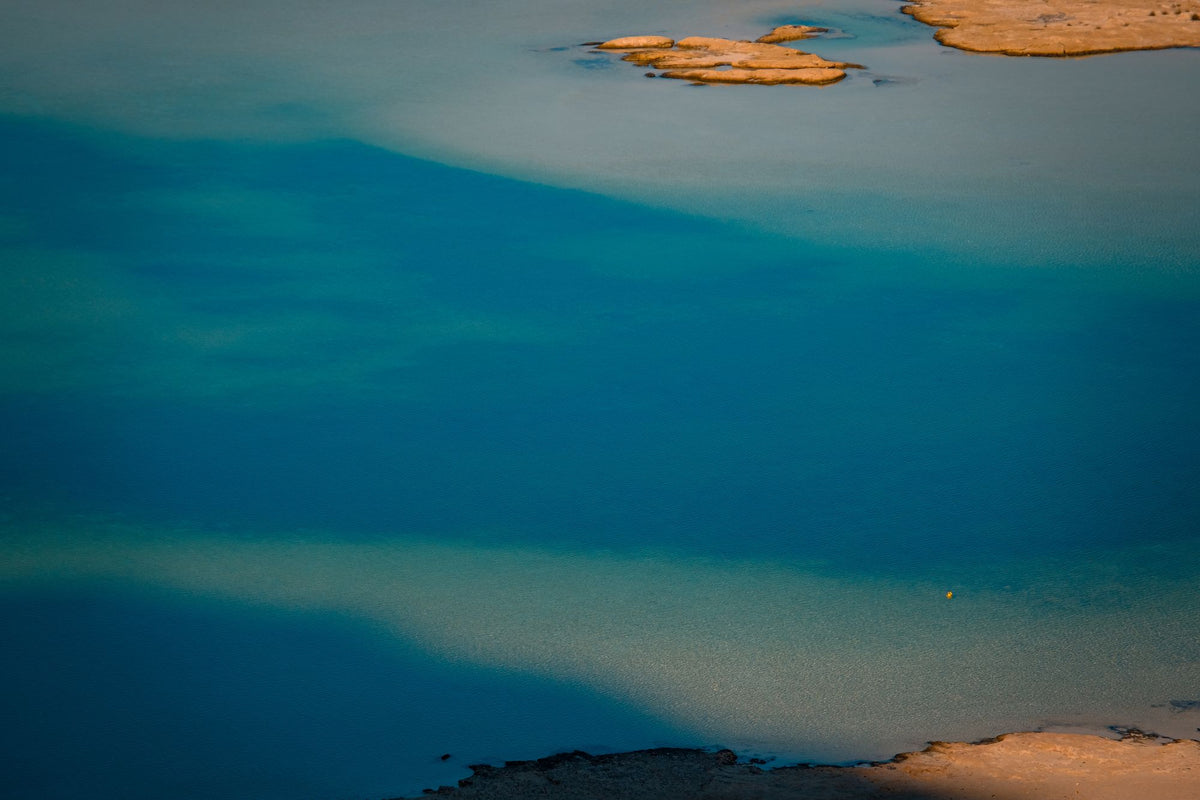 Clear teal water meeting pale stone at a pool edge, evoking the cool side of a contrast therapy water circuit