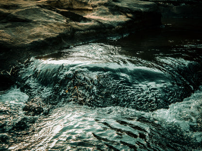 Cold spring water running clear over dark rock, The Meadow Spa at Thyme, Southrop