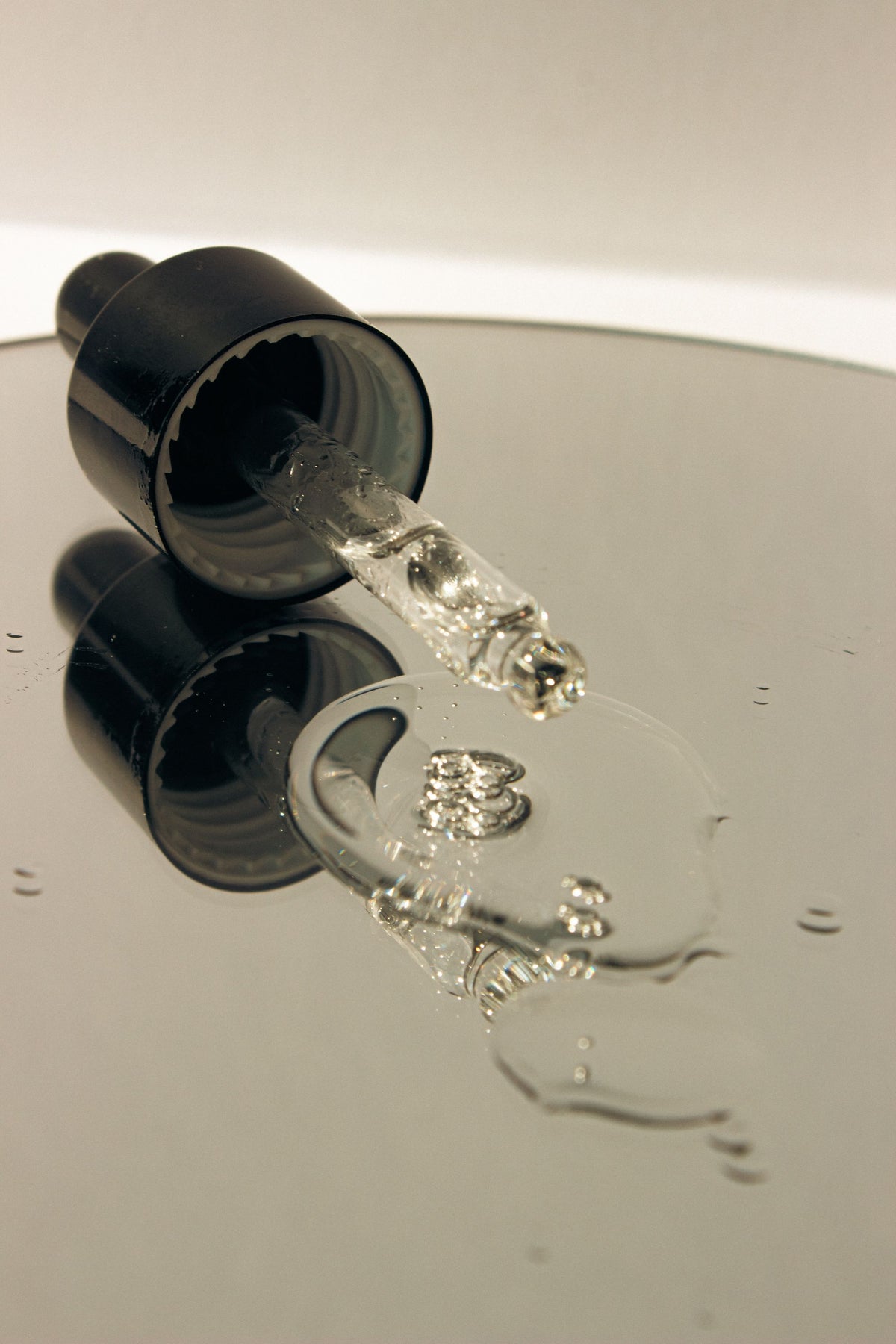 A clear dropper of facial serum catching the light