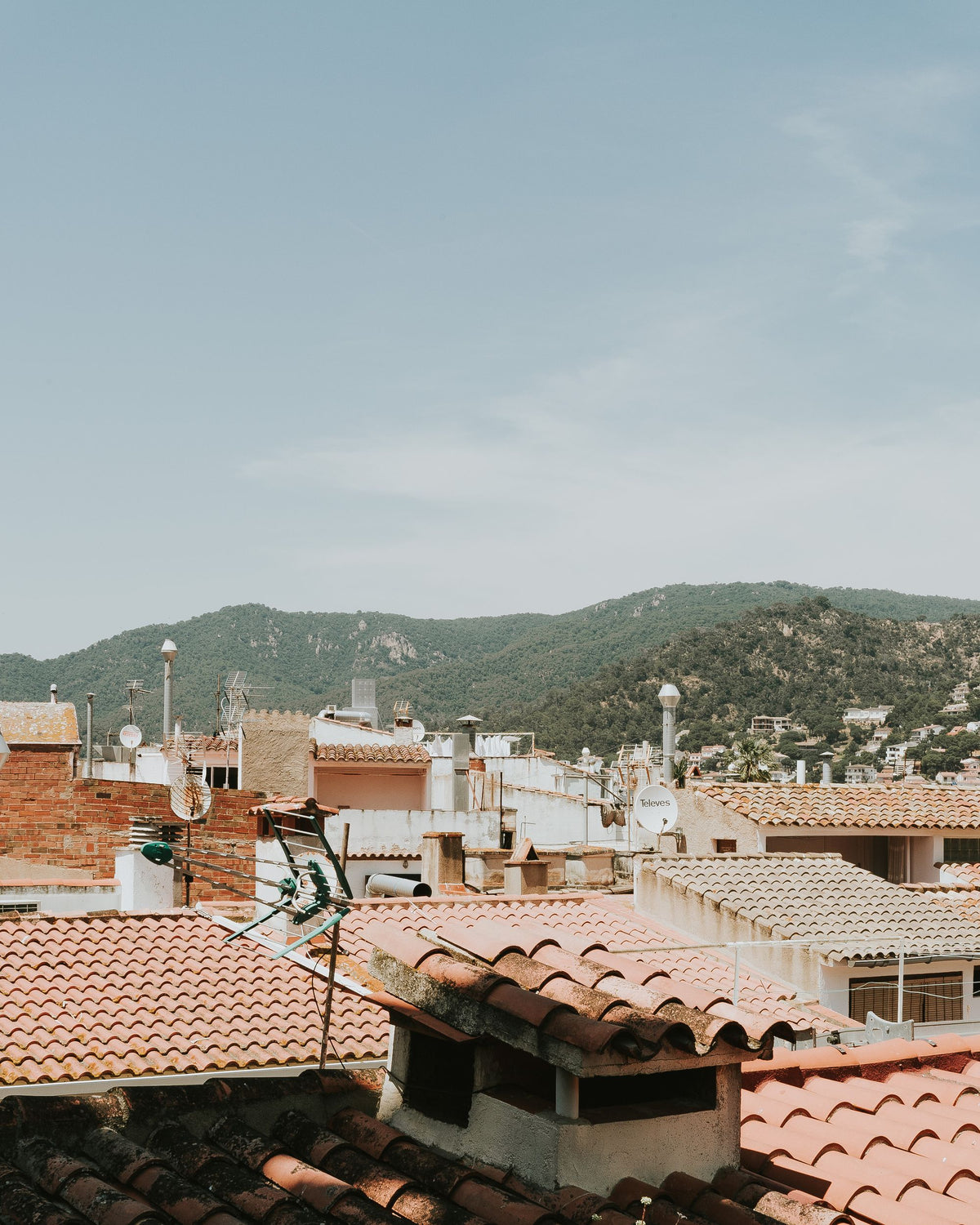 Terracotta rooftops of a Spanish hillside village against green mountains