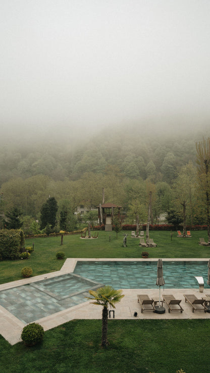 A misty outdoor pool set into lush forest grounds