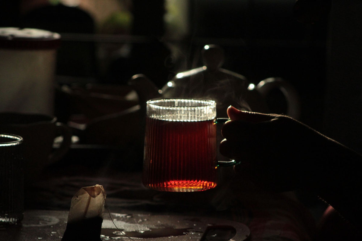 Steam rising from a glass of herbal tea in warm low light