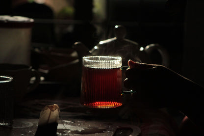 Steam rising from a glass of herbal tea in warm low light