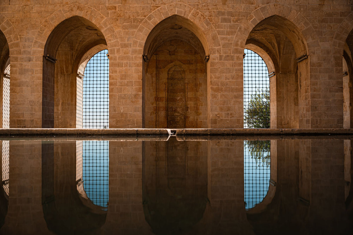 A still reflecting pool beneath a row of stone arches