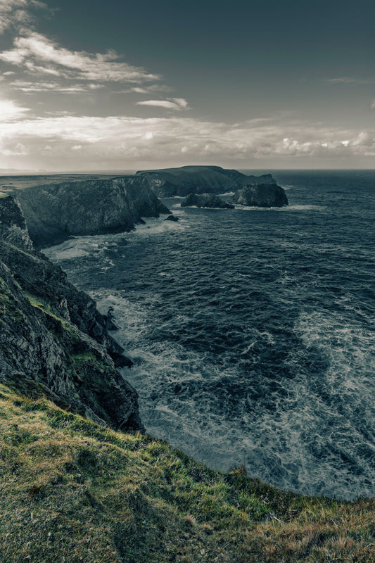 Dramatic Atlantic cliffs meet the sea under a moody Irish sky.