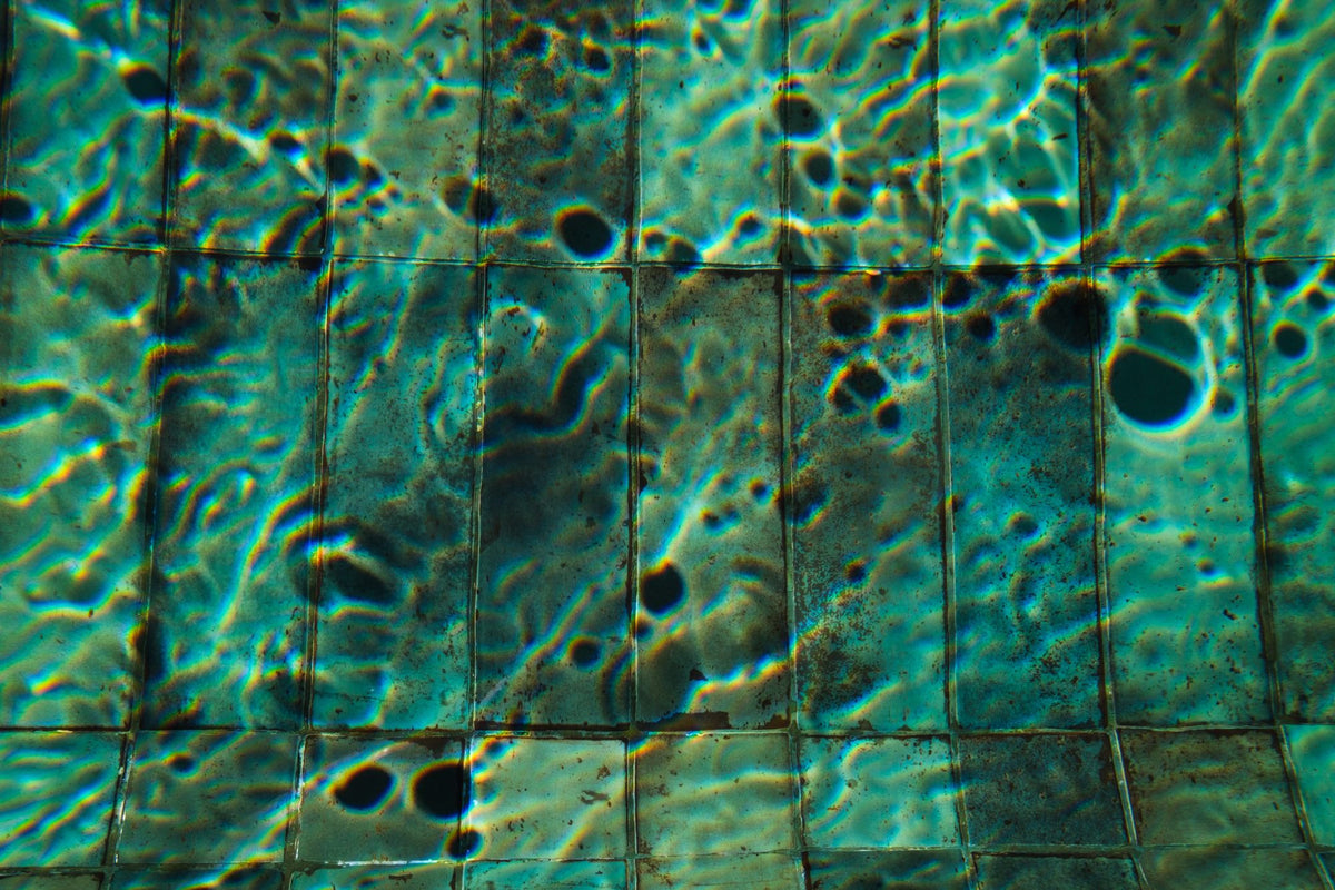Close up of rippling water over teal glazed pool tiles