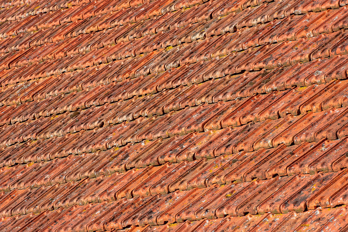 Close up of weathered terracotta roof tiles in warm Tuscan sunlight