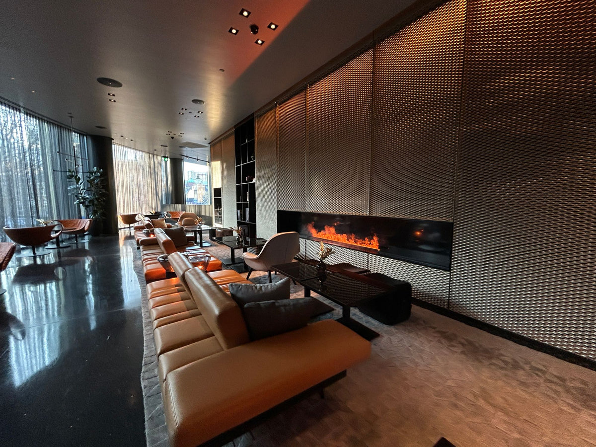 A sleek modern lounge with a glowing fireplace and leather seating