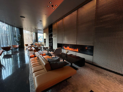A sleek modern lounge with a glowing fireplace and leather seating
