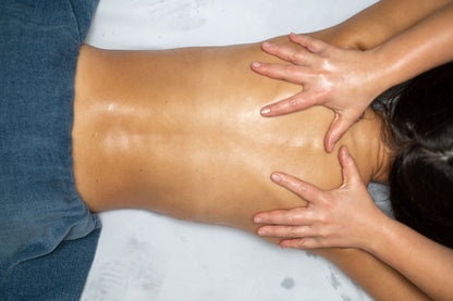 A therapist's hands giving a back massage with oil