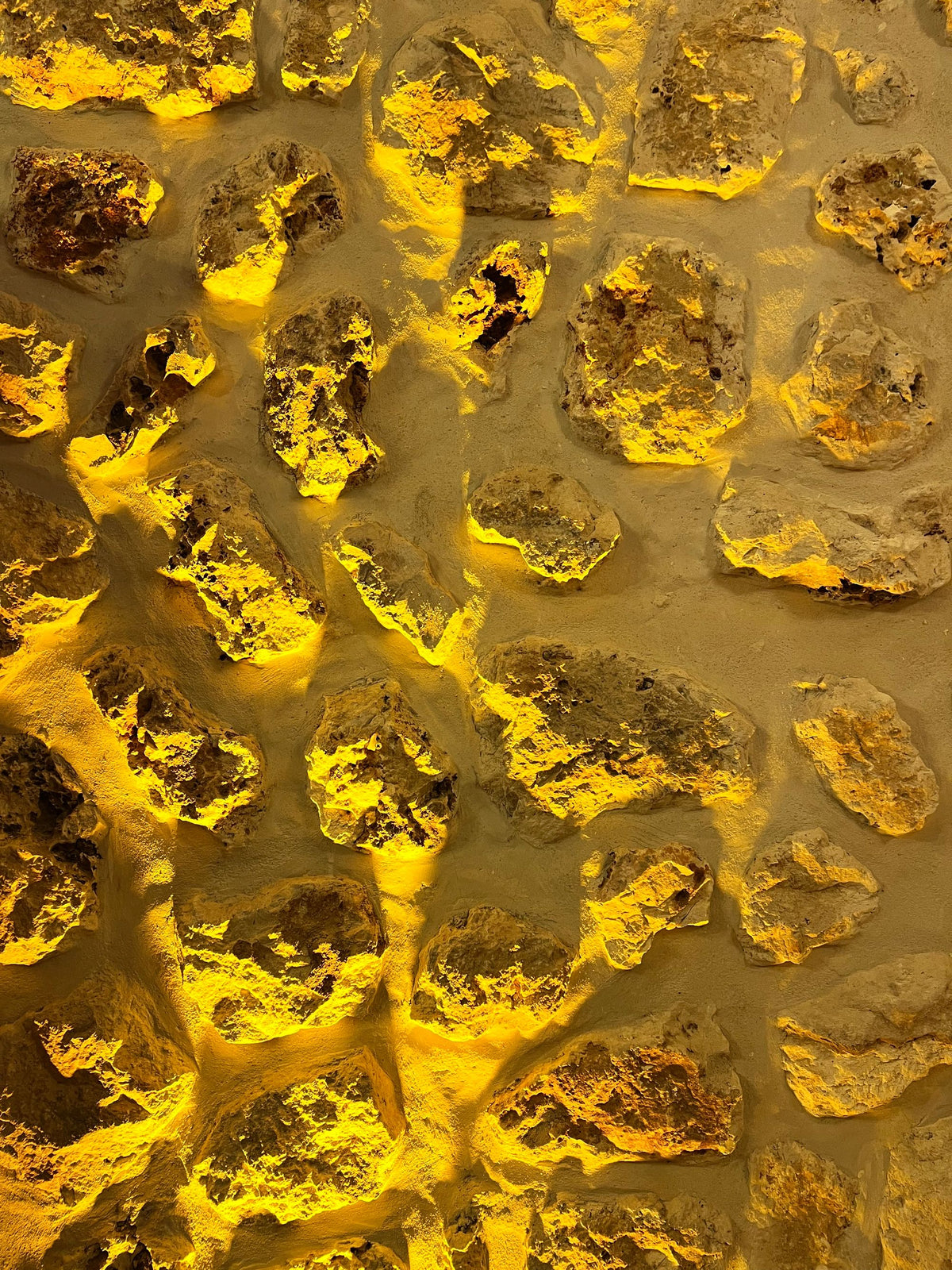 Close up of warm honey toned stone wall texture with dramatic lighting