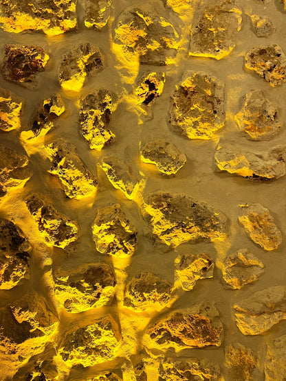 Close up of warm honey toned stone wall texture with dramatic lighting