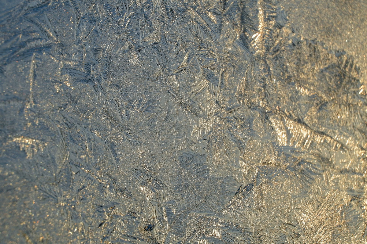 Close up of icy frost crystals catching golden light, evoking the cold plunge after the heat circuit