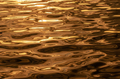 Warm gold light rippling across water, evoking sunlight on the skylit pond at Arlington Baths Club
