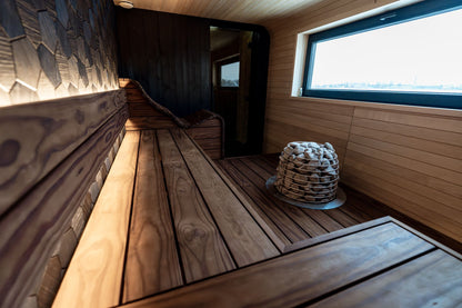 A wood panelled sauna with a heap of stones warming in the corner