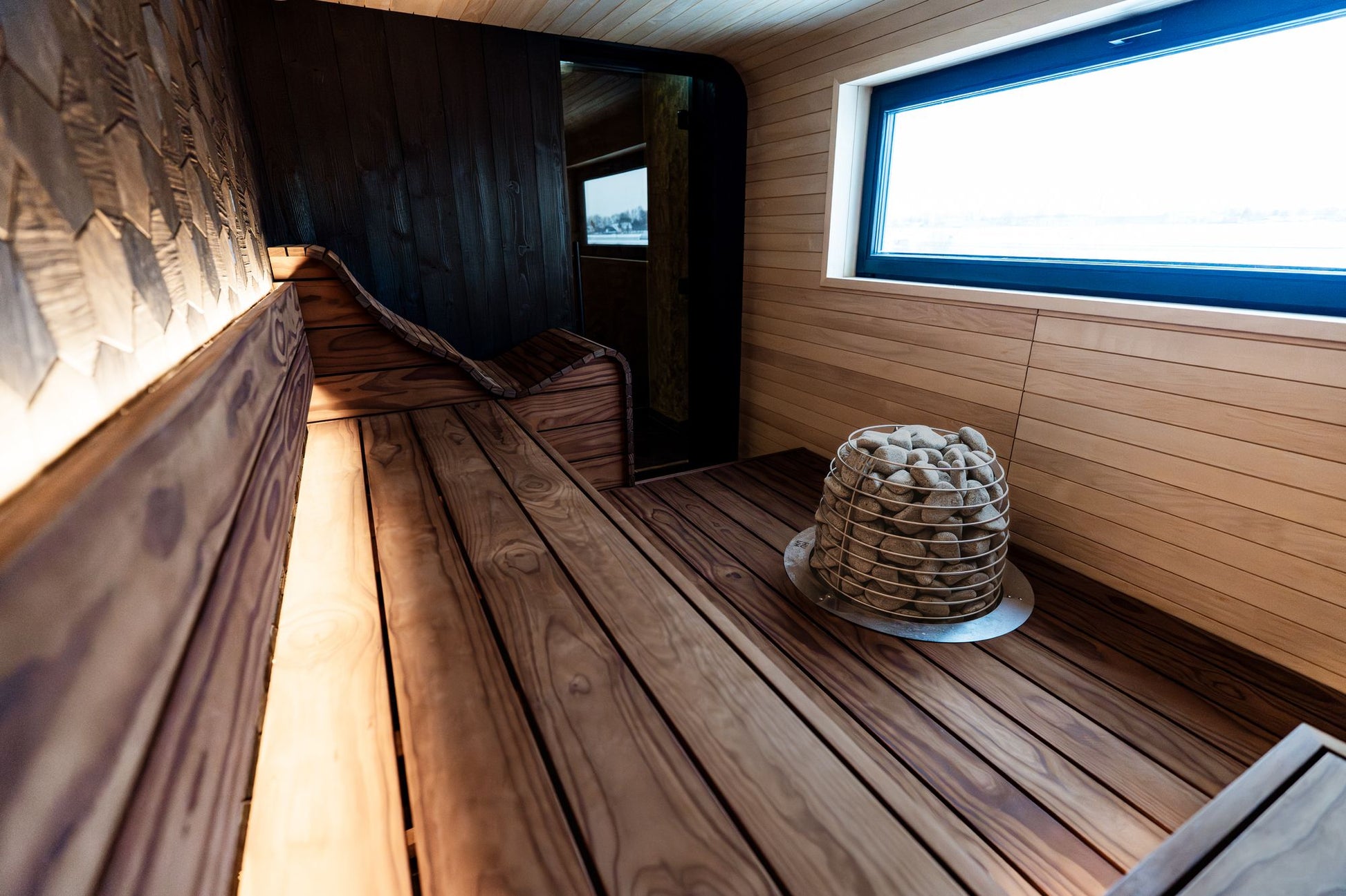 A sauna lined in warm timber with a window at the far end, standing for the windowed sauna and its Himalayan salt wall