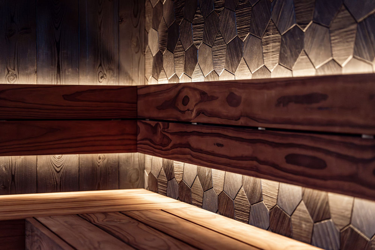 A hand crafted timber sauna interior with warm low lighting and geometric wood panelling