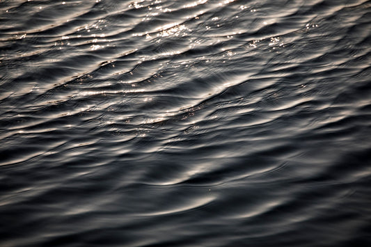 Dark rippling water catching warm light, evoking the thermal springs that feed the kaolin clay pools at Les Prés d'Eugénie
