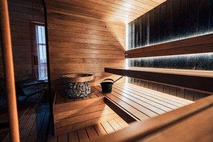 A dark wood sauna interior with heated stones, part of the thermal circuit at Spa La Mer.