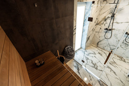 A modern sauna interior with marble and wood, evoking the heat side of the spa