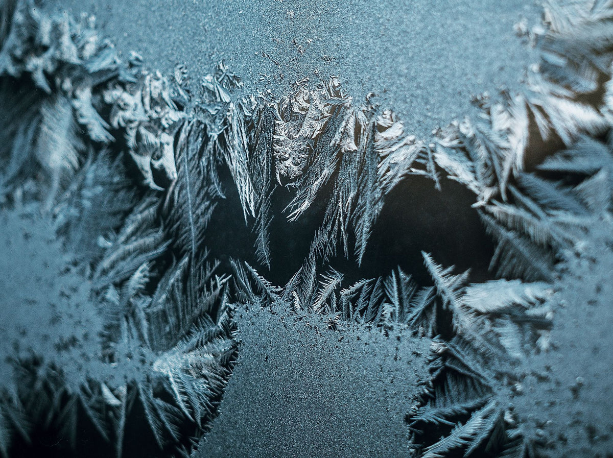Intricate frost patterns on glass, evoking the cold plunge after the warm bath