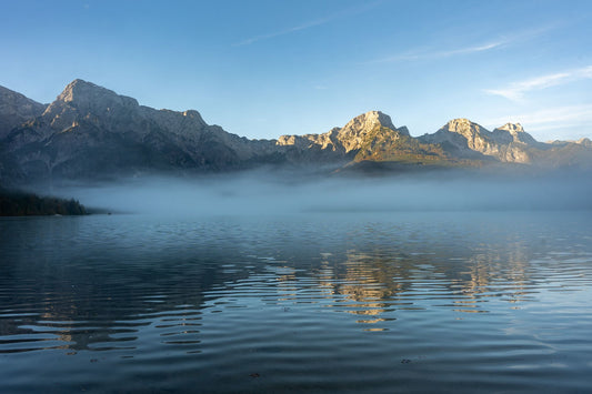 A misty lake reflecting mountains at sunrise, evoking the view over Lough Lein from ESPA at The Europe