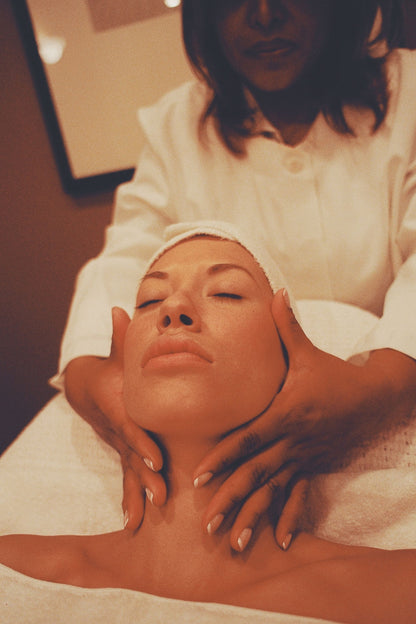A therapist's hands cradling a guest's face during a facial treatment