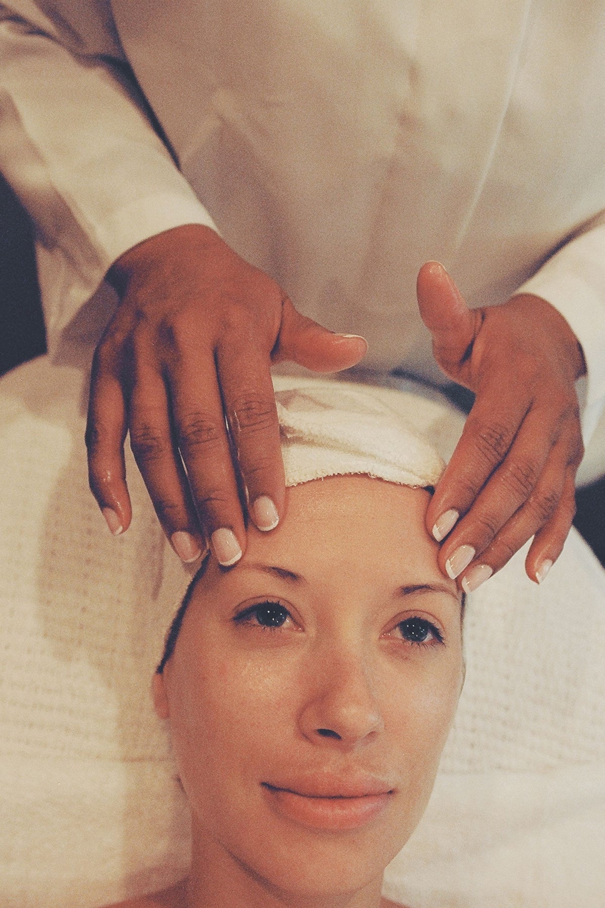 A facial treatment in progress with calm, pale toned styling, evoking a spa treatment room
