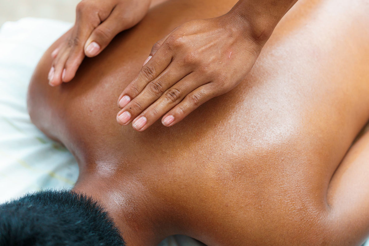 A therapist's hands working across an oiled back during a massage