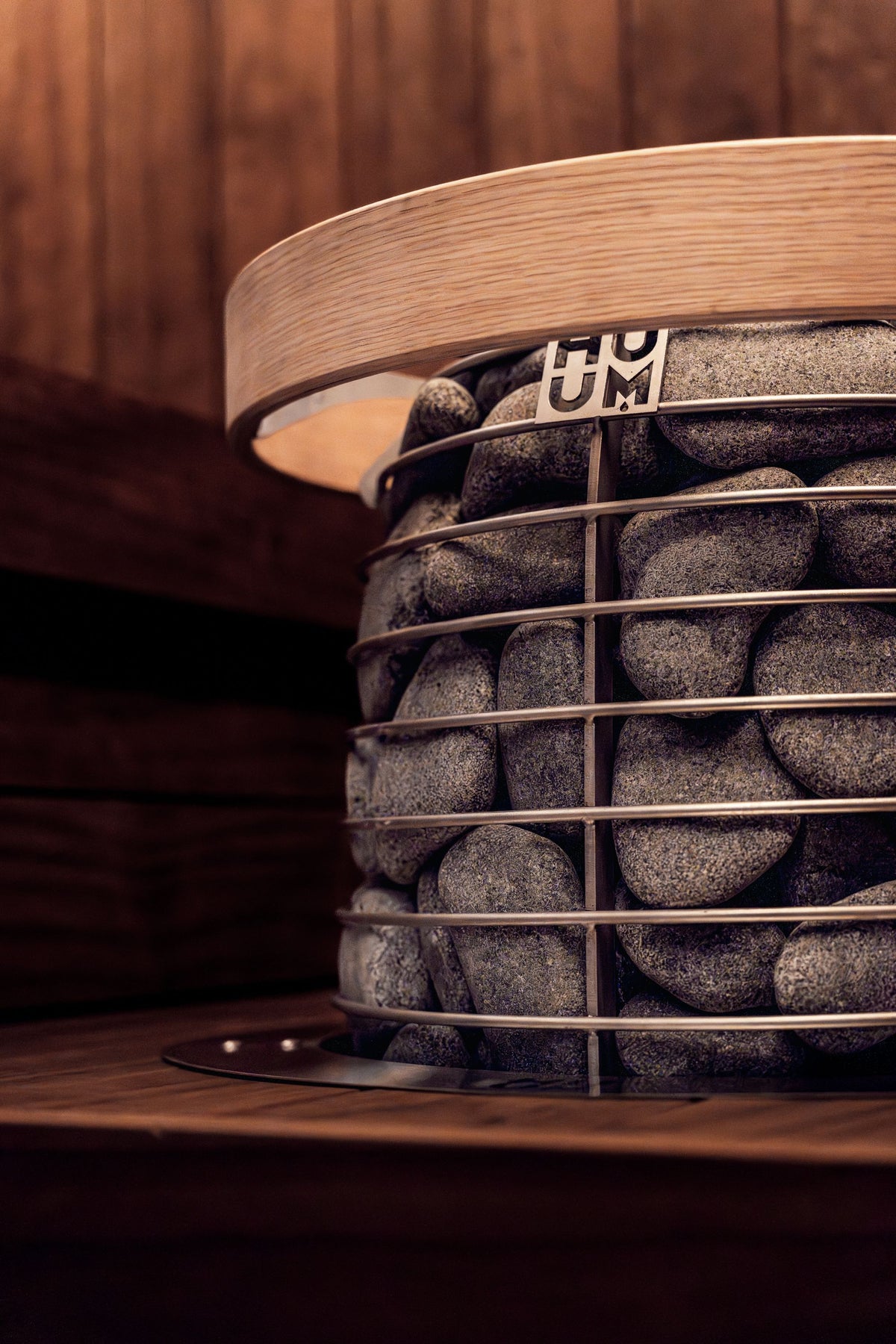 A sauna heater stacked with stones in warm low light, evoking the heat side of the spa